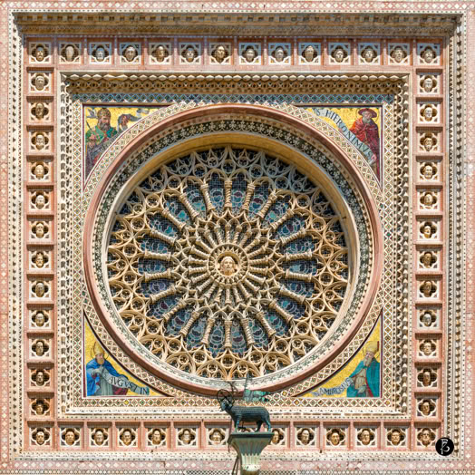 Rosone decorato con motivi geometrici e dettagli colorati, incorniciato da un elaborato bordo rettangolare.