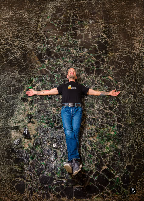 Persona sdraiata su una superficie rocciosa con le braccia aperte, indossa una maglietta nera e jeans blu.