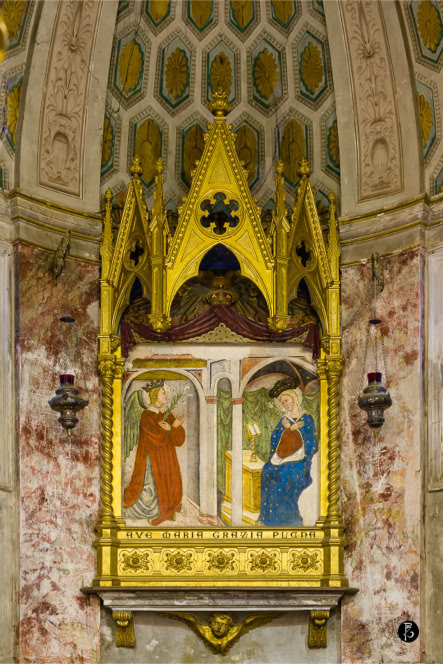 Dipinto religioso con due figure in abiti storici all'interno di una cornice dorata, situato su una parete decorata.